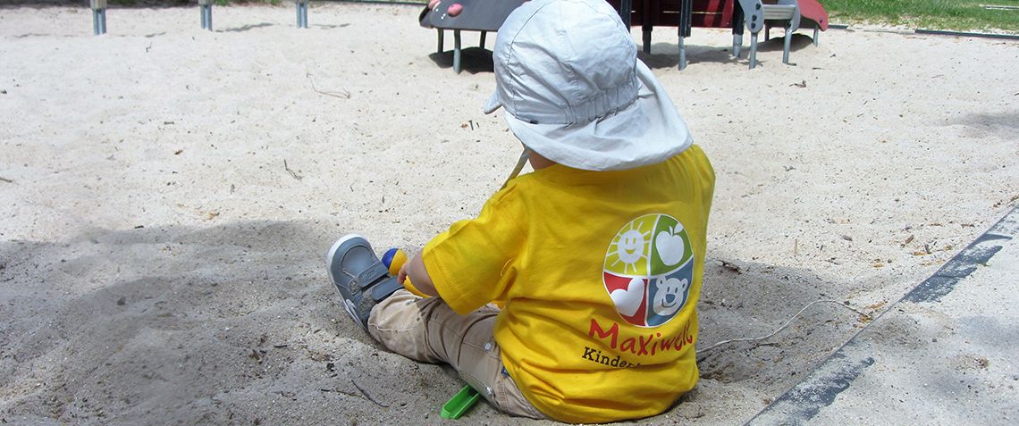Maxiwelt Kinderbetreuung - Kind sitzt im Sand